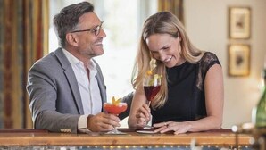 A couple at a bar with a well-lit interior, glasses on the counter, and a window in the background. - Wellnesshotel Schonruh - Adults Only (Seefeld in Tirol)