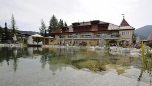 A hotel with a large building, a pond, and outdoor seating. - Wellnesshotel Schonruh - Adults Only (Seefeld in Tirol)