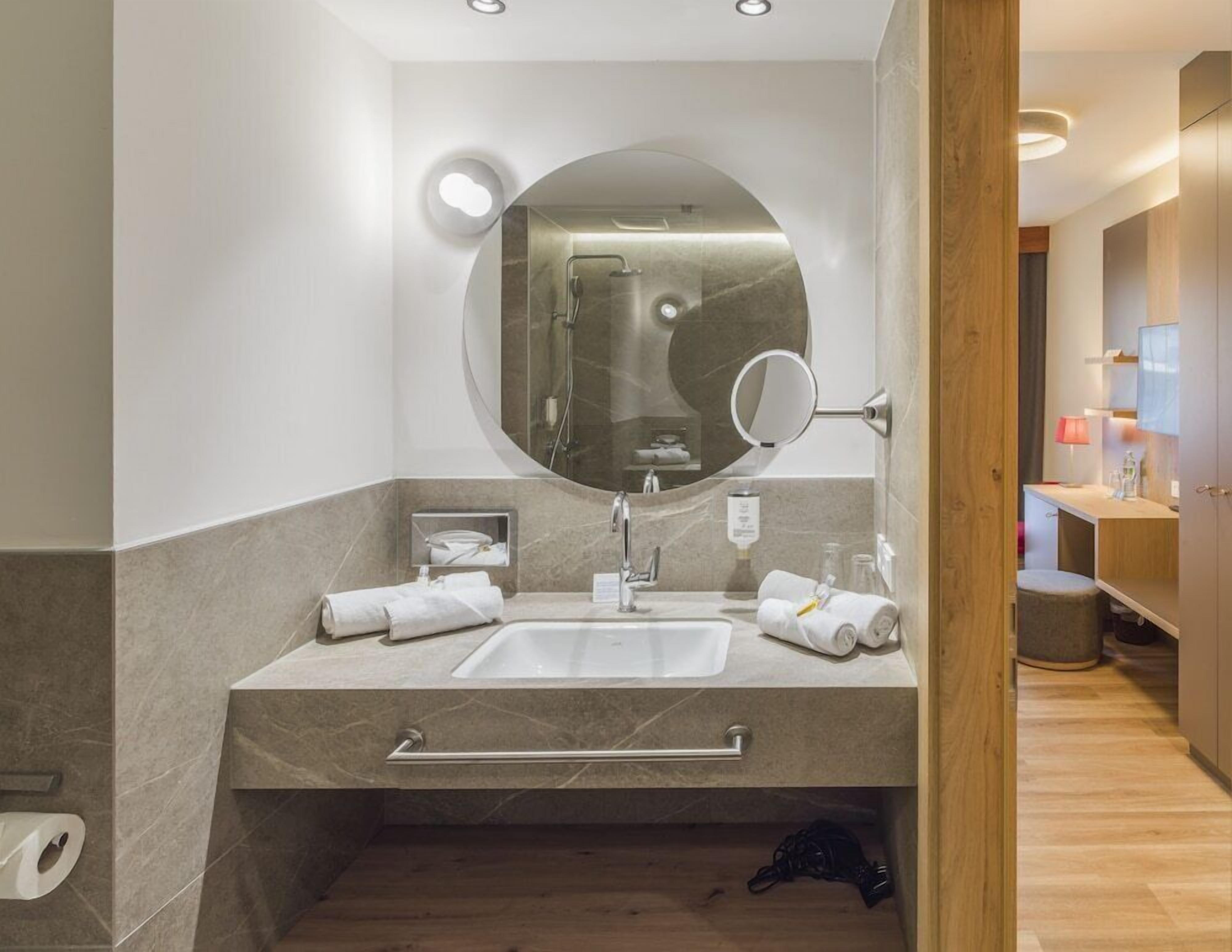 Une salle de bain moderne avec un grand miroir, un lavabo et une douche.