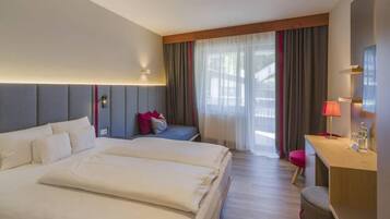 A hotel room with two beds, a desk, a chair, and a large window with curtains.