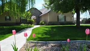 A residential house with a stone facade, a front yard with a pathway, and pink tulips. - Perfect Moments B&B and Event Venue (Nampa)