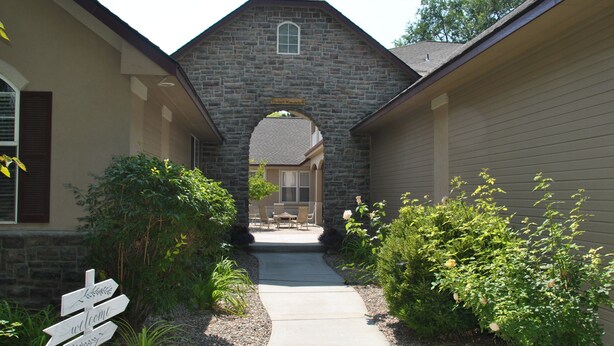A stone archway leading to a house with a signpost indicating directions. - Perfect Moments B&B and Event Venue (Nampa)