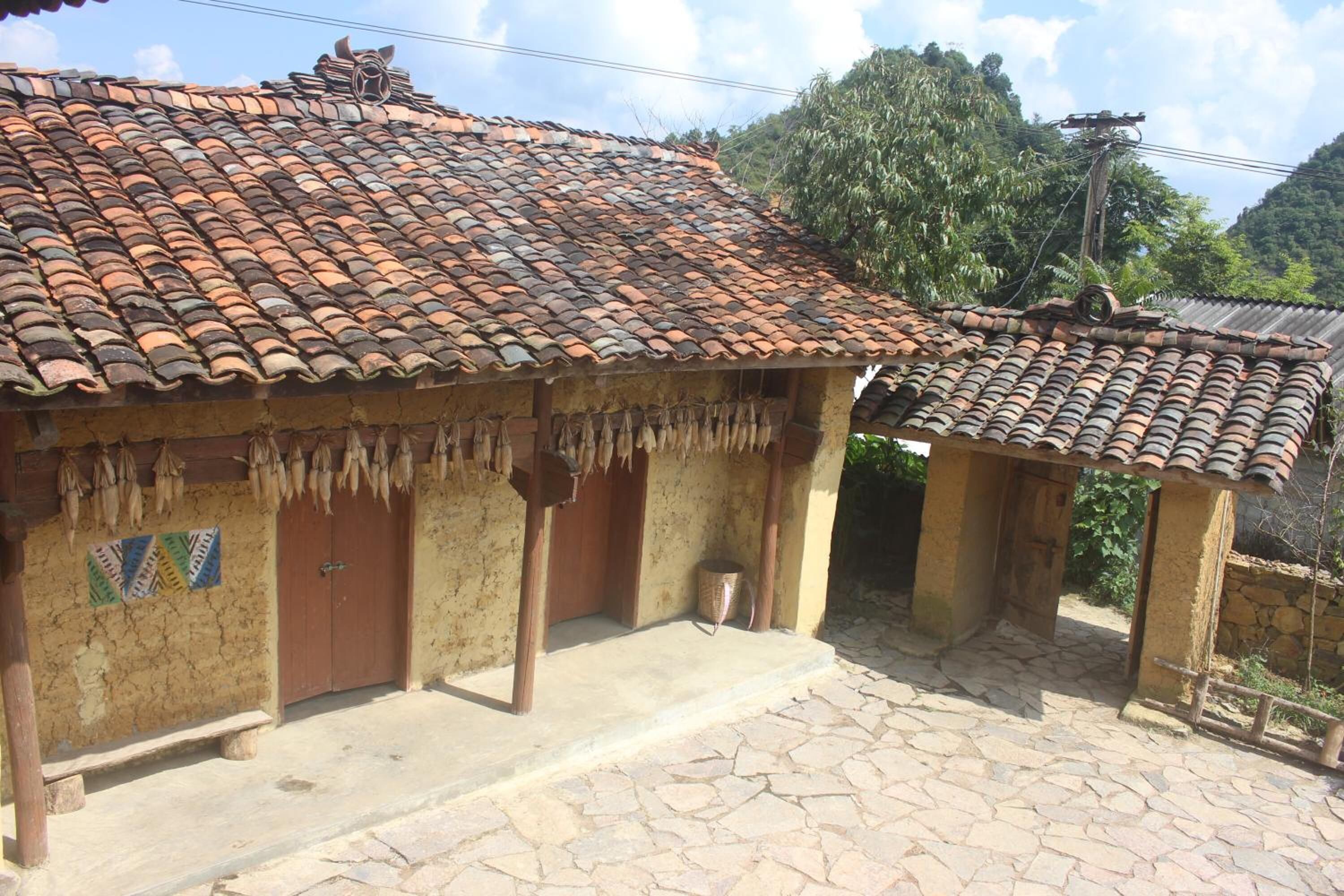 A traditional house with a tiled roof and a thatched roof structure.