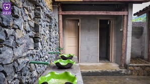 Un muro in pietra con tre ciotole verdi in ceramica allineate su una mensola.