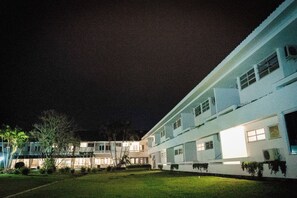 Et hotel med flere etager, en godt oplyst facade og en græsplædehave.