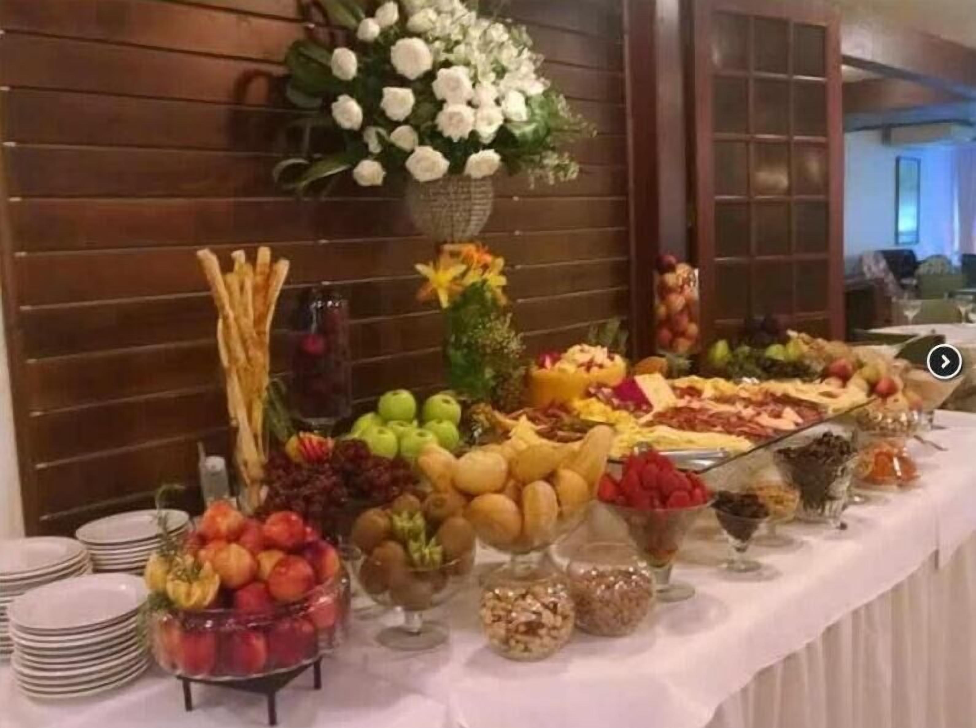 A buffet table with various fruits, cheeses, and desserts.