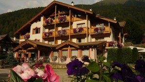 Un hotel de varios pisos con balcones decorados con macetas de flores, con montañas al fondo.