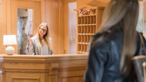 Un mostrador de recepción de madera con un espejo y una repisa con objetos decorativos.