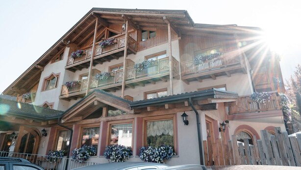 Un edificio de varios pisos con balcones de madera, macetas con flores y un estilo arquitectónico tradicional.