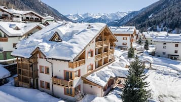 Ein schneebedecktes Bergresort mit Holzbauten und freiem Blick auf die Berglandschaft im Hintergrund.