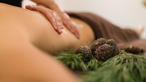 Eine Massage mit Kiefernadeln und grünem Laub auf einer Massageliege.