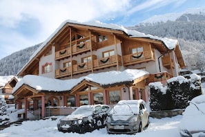 Un chalet de madera de varios pisos con balcones, rodeado de montañas nevadas.