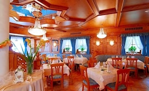 Un restaurant au décor intérieur en bois, doté de nombreuses tables et agrémenté de lustres suspendus.
