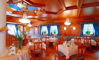 Un restaurant au décor intérieur en bois, doté de nombreuses tables et agrémenté de lustres suspendus.