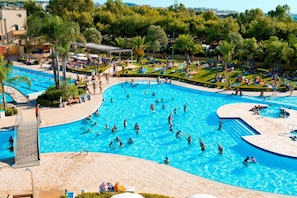 A large outdoor swimming pool surrounded by palm trees and lounge areas. - Happy Camp in Camping La Masseria (Gallipoli)