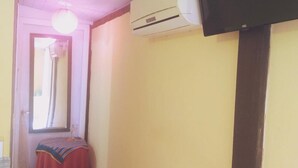A narrow hallway with a checkered floor, a small table with a colorful cloth, and an air conditioning unit mounted on the wall. - Pousada Tonapraia (Florianópolis)