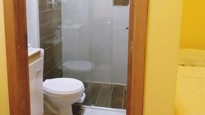 A bathroom with a glass-enclosed shower, a toilet, and a small window. - Pousada Tonapraia (Florianópolis)