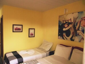 Habitación de hotel con dos camas, un cuadro abstracto grande en la pared y dos fotografías enmarcadas.