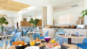 A modern hotel dining area with multiple tables, chairs, and a buffet with breakfast items. - Best Western La Marina (Saint-Raphael)