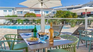 A poolside dining area with a table set for two, a bottle of wine, and a glass of water. - Best Western La Marina (Saint-Raphael)