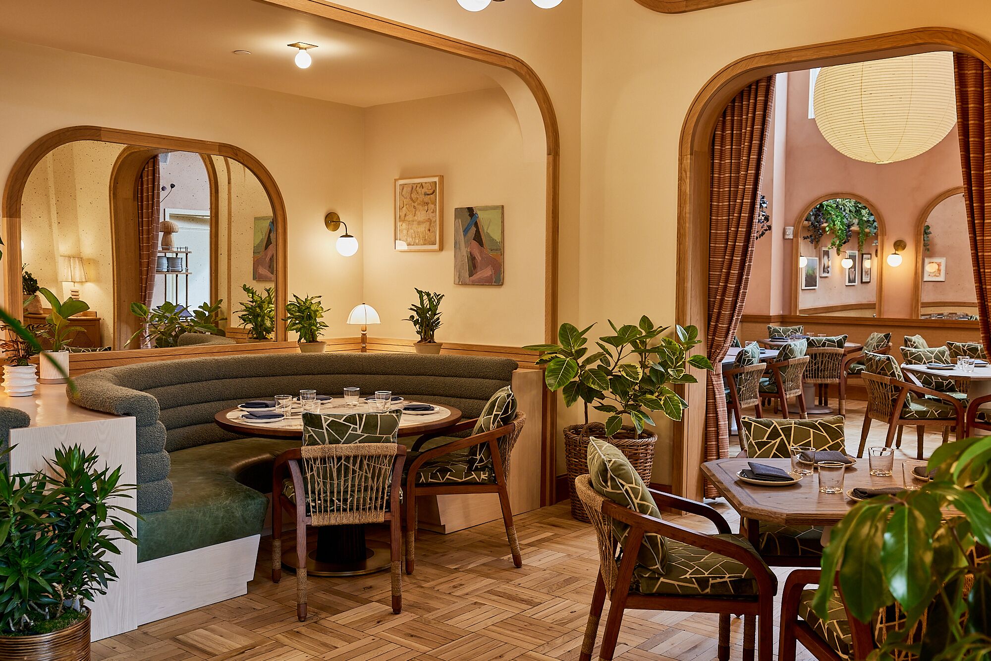 A cozy dining area with a round table, cushioned seating, and potted plants.