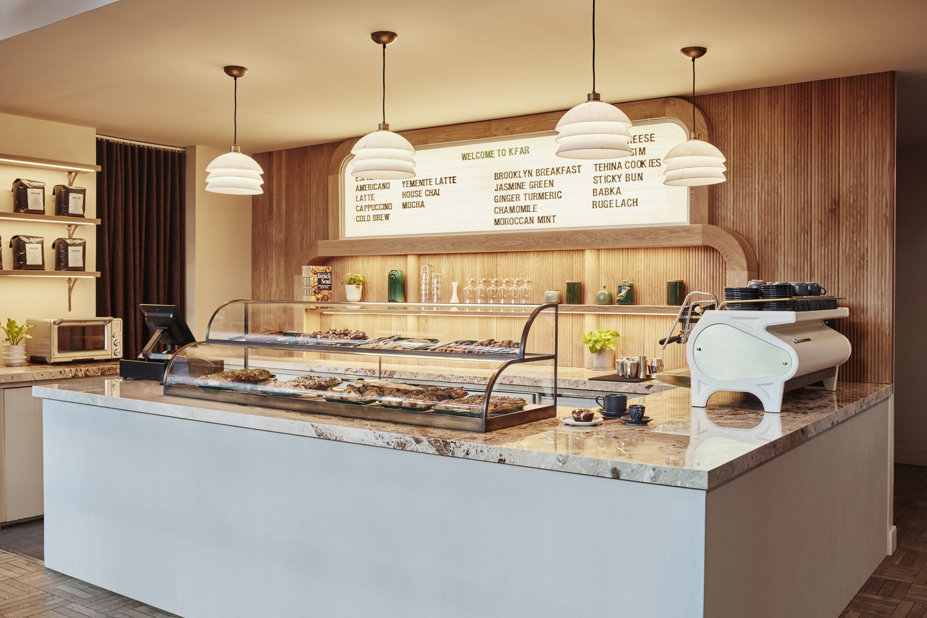A bakery counter with a variety of baked goods and a menu listing items like Americanos, Yemeni lattes, and Moroccan mint.
