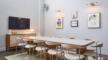 Una sala riunioni moderna con un lungo tavolo, sei sedie, un televisore e diverse opere d'arte incorniciate alle pareti.