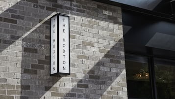 En bygningsfacade med en murstensvæg og et skilt, der står "The Hoxton 97".