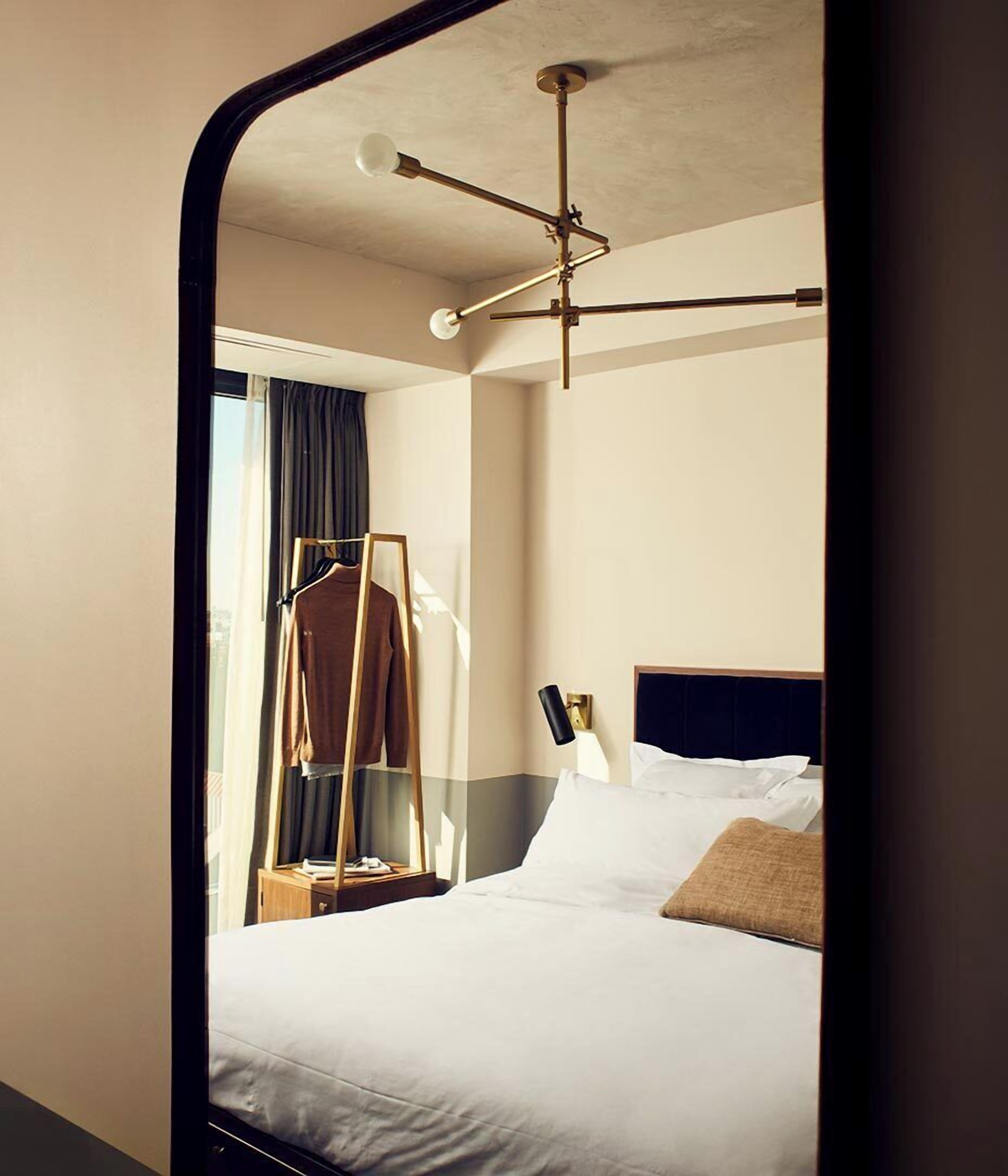 Una habitación de hotel con cama, lámpara colgante, mesita de noche y armario.