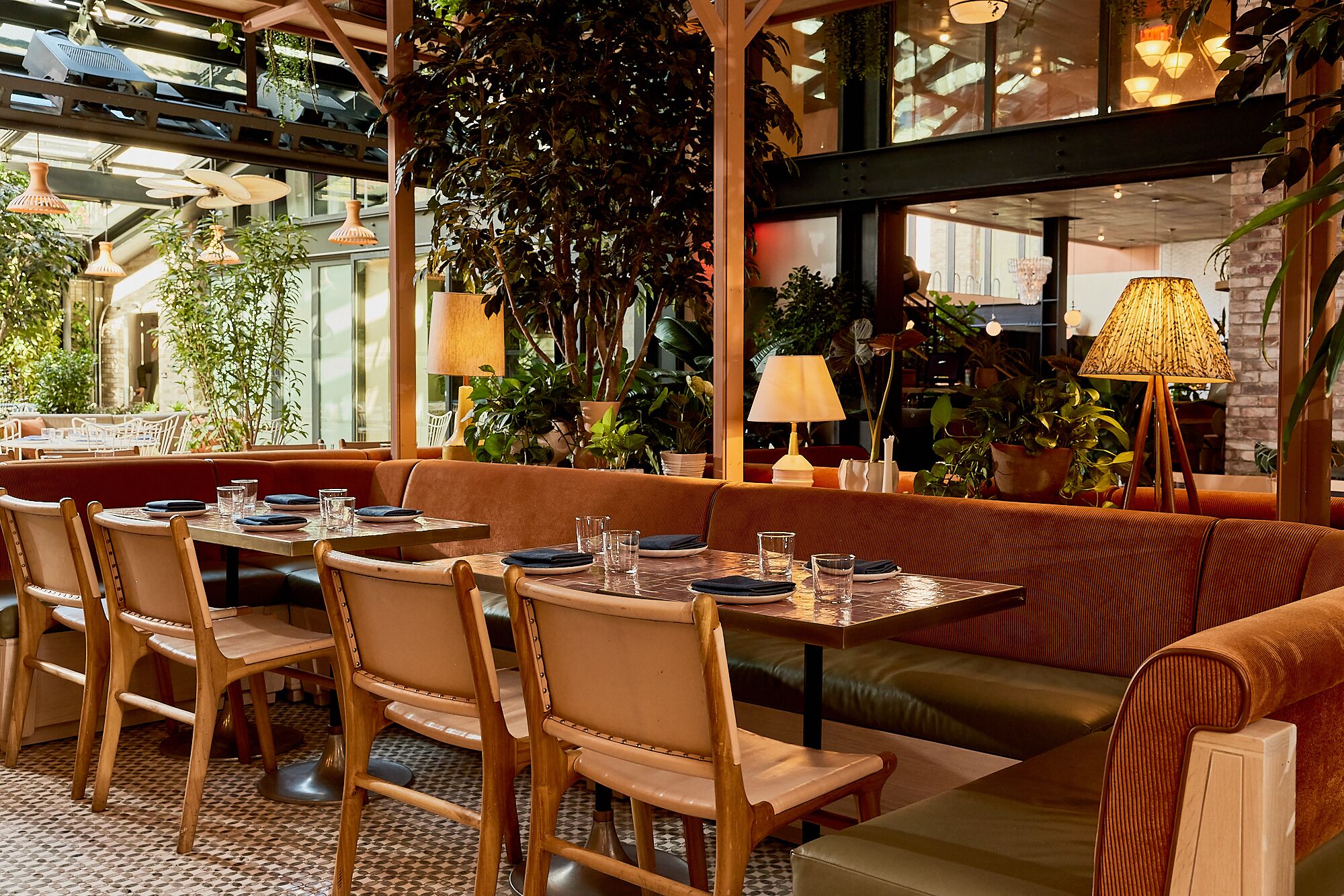 A restaurant with wooden furniture, potted plants, and hanging lamps.