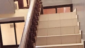 Una escalera con balaustres de madera y peldaños color beige.