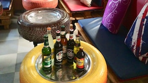 Una habitación acogedora con un sofá, una mesa con botellas y una ventana con vistas a árboles.