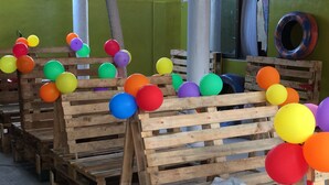 Tarimas de madera apiladas con globos de colores.