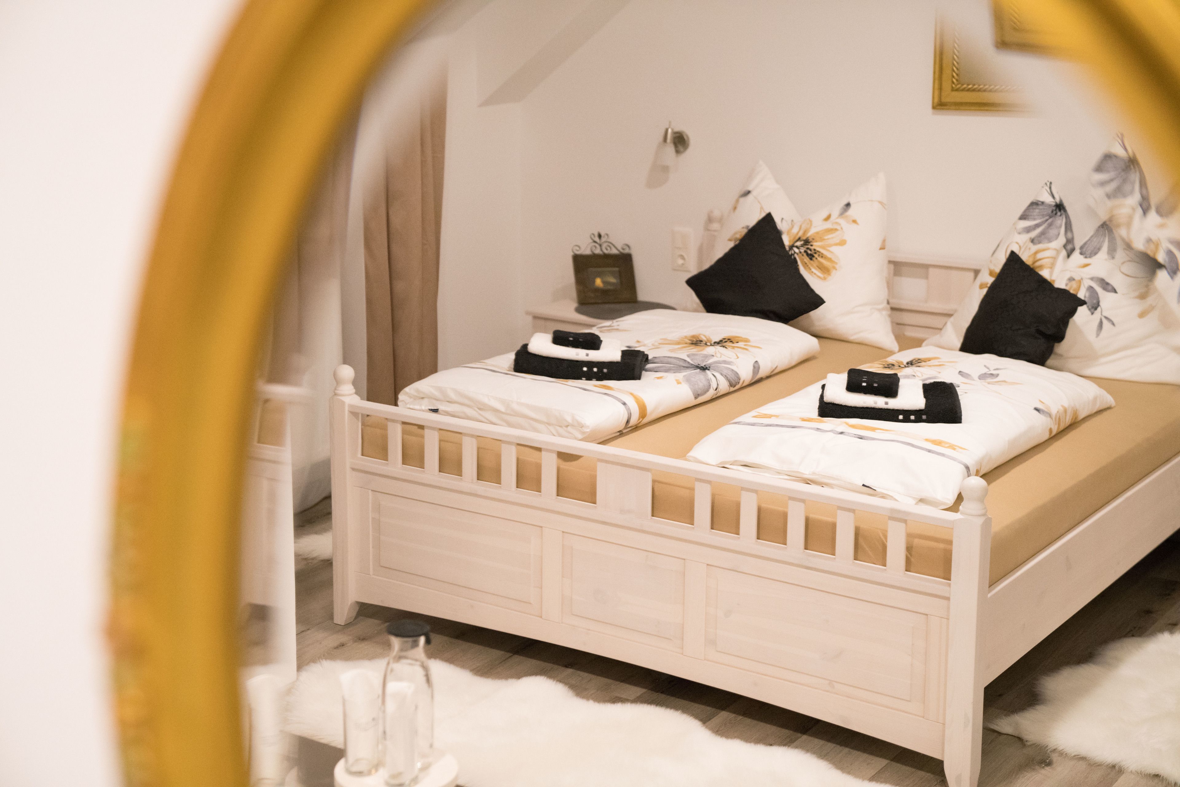 Un dormitorio con una cama blanca, dos almohadas, una mesita de noche y un espejo.