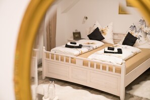 A bedroom with a white bed, two pillows, a bedside table, and a mirror. - Pension & Restaurant La Amalia (Bad Sauerbrunn)