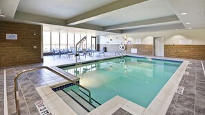 An indoor swimming pool with a lifeguard station, a changing room, and a seating area with tables and chairs. - Hilton Garden Inn Gastonia (Gastonia)