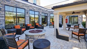 An outdoor patio area with stone walls, large windows, and outdoor seating. - Hilton Garden Inn Gastonia (Gastonia)