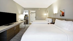 A hotel room with a flat-screen TV, a desk with a lamp, two beds, a nightstand, and a painting on the wall. - Hilton Garden Inn Gastonia (Gastonia)