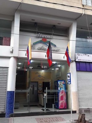Ein Hotel Eingang mit Glastür, einem Schild darüber und einer Flagge, die von der Decke hängt.