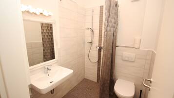 Un baño moderno con ducha, inodoro y lavamanos.