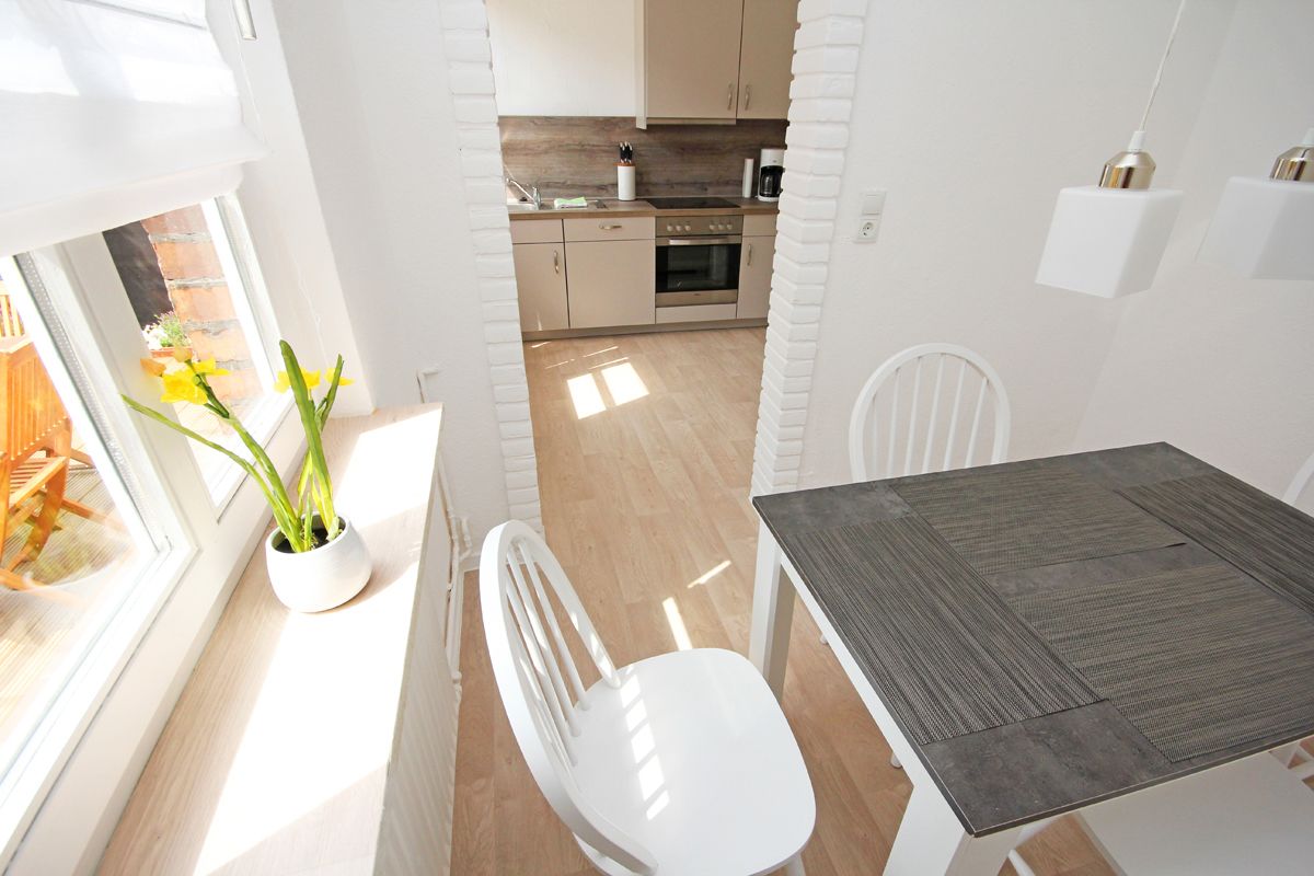 A modern kitchen with light wood cabinets, a dark countertop, and a window with a view of the outside.