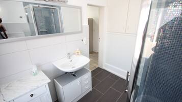 Une salle de bain avec un lavabo blanc, un miroir et un sol carrelé.
