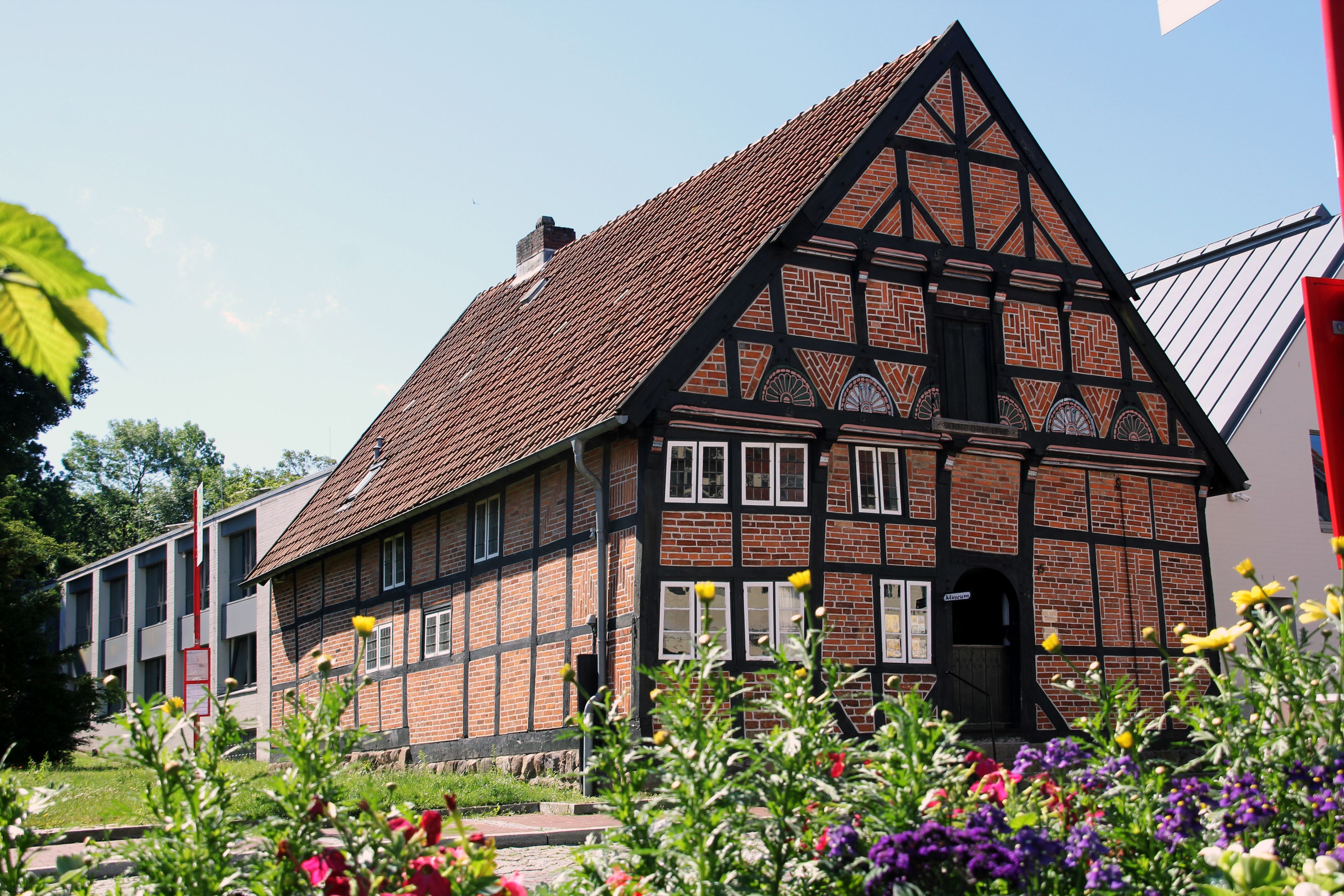 A traditional half-timbered house with a steeply pitched roof, a visible chimney, and a small entrance door.
