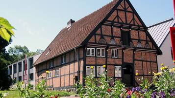 A traditional half-timbered house with a steeply pitched roof, a visible chimney, and a small entrance door.