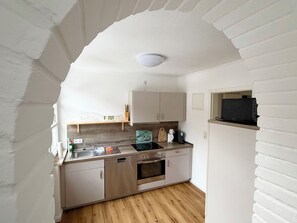 Een kleine keuken met een houten aanrecht, roestvrijstalen apparatuur en witte kasten.