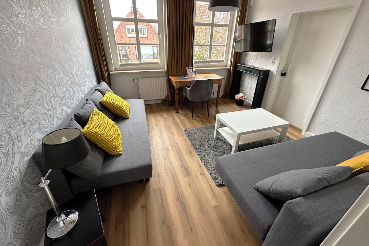 Ein modernes Wohnzimmer mit einer Couch, einem Couchtisch, einem Fernseher und einem Kamin.