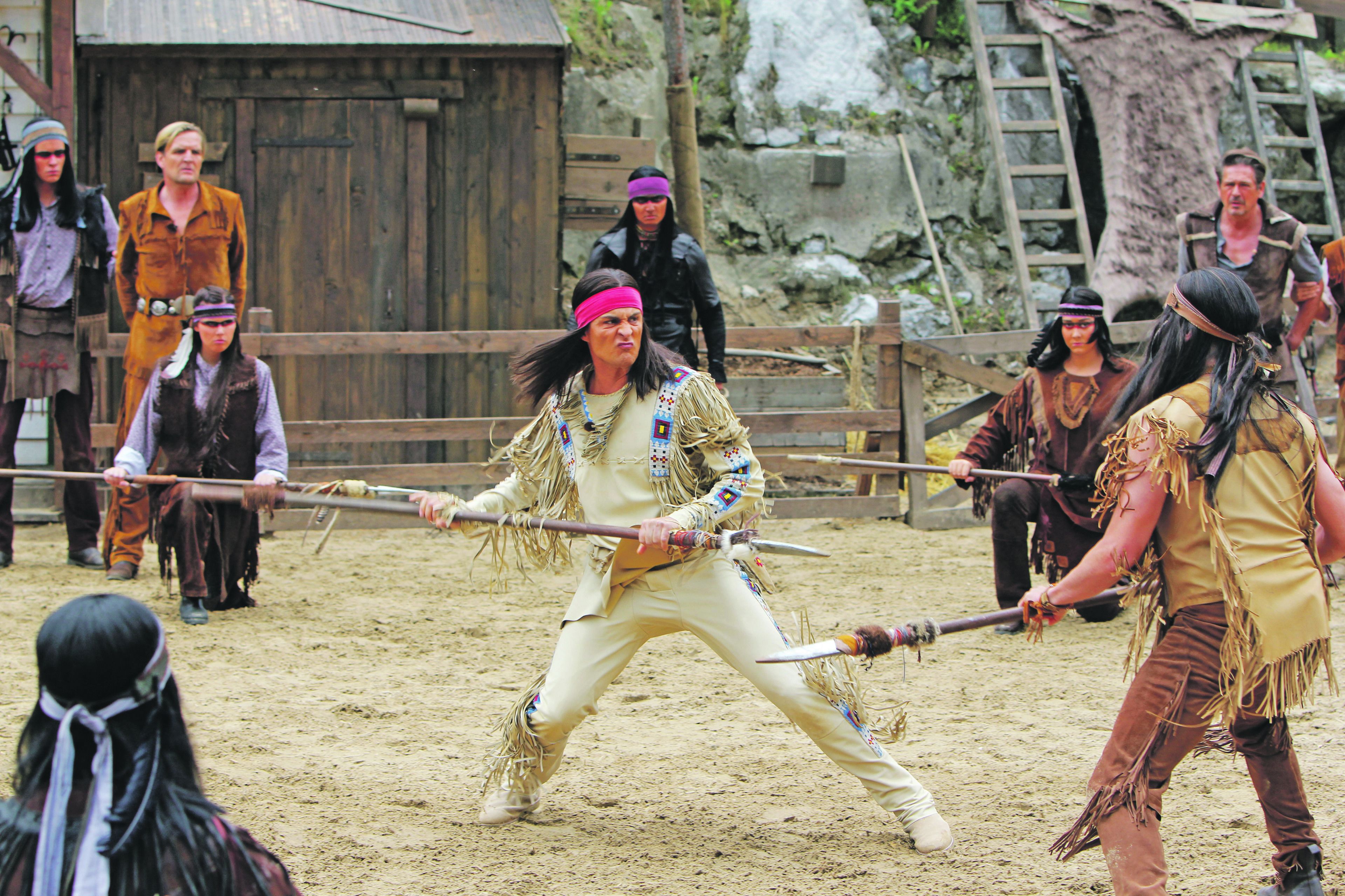 A group of people in a sandy outdoor setting, possibly a historical reenactment or themed event.