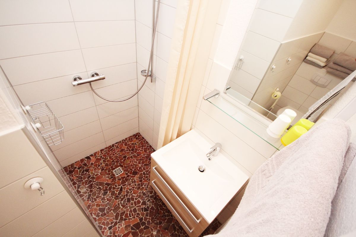 A bathroom with a shower, a sink, and a mirror.