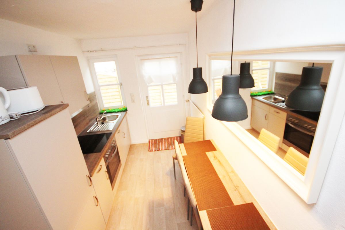 A compact kitchen with a wooden countertop, a sink, and a window above the stove.