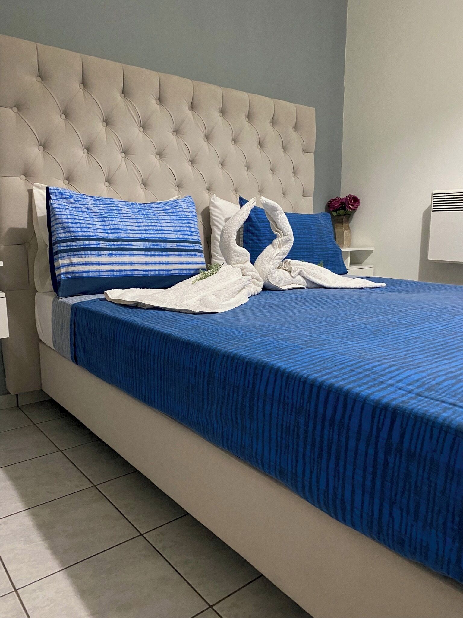 A bed with a tufted headboard, blue bedding, and decorative pillows.